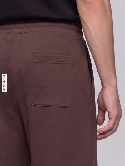 Männermodel trägt Relaxed Fit Sweathose aus reiner Baumwolle Modell 'Devropant' von HUGO, braun, Herren Weite Hose, Nahaufnahme Rückansicht, KI-modifiziertes Bild.