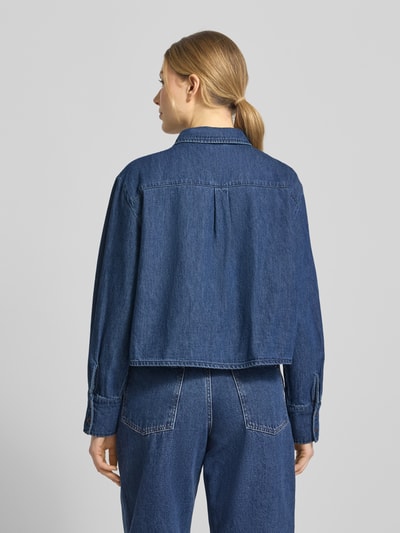 Vrouwenmodel draagt Cropped Jeansbluse uit puur katoen model 'POSEY' van Vero Moda, denimlook, boxy fit, lange mouw, achteraanzicht.