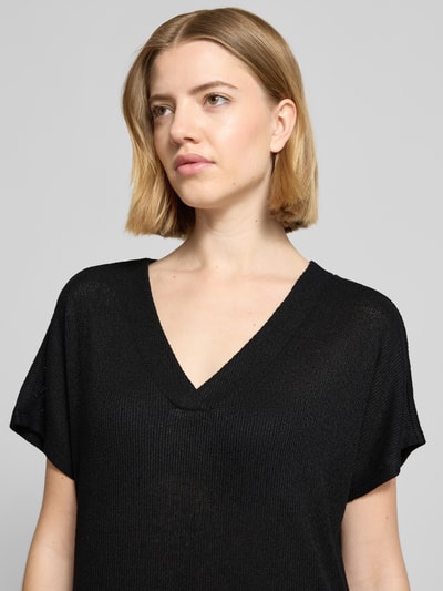 Frauenmodel trägt Strickkleid mit V-Ausschnitt Modell 'Delia' von Soyaconcept, schwarzer Viskose-Mix mit feiner Rippenstruktur, Gerader-Schnitt, Nahaufnahme Oberkörper. Midikleid mit Stretch-Anteil, Rückenlänge bei Größe S 112 cm, Brustweite 54 cm, Ärmellänge 24 cm.