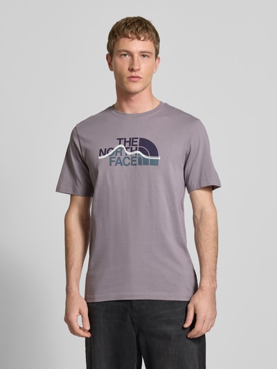 Männermodel trägt Regular Fit T-Shirt aus reiner Baumwolle Modell 'MOUNTAIN LINE' von The North Face in Grau mit Label-Print, Ganzkörperansicht von vorne. Herren T-Shirt mit Rundhalsausschnitt, Rückenlänge bei Größe M 70 cm.