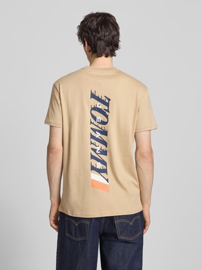 Männermodel trägt Regular Fit T-Shirt aus reiner Baumwolle von Tommy Jeans, unifarben, Label Print, Jersey Struktur, Ganzkörperansicht Rückansicht.