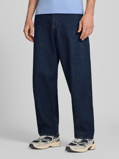 Männermodel trägt Barrel fit Jeans aus Baumwoll-Mix Modell 'ASHTON' von Tommy Jeans, dunkles Blau, lockere Passform, Ganzkörperansicht von vorne, Herren Barrel Jeans von Tommy Jeans.