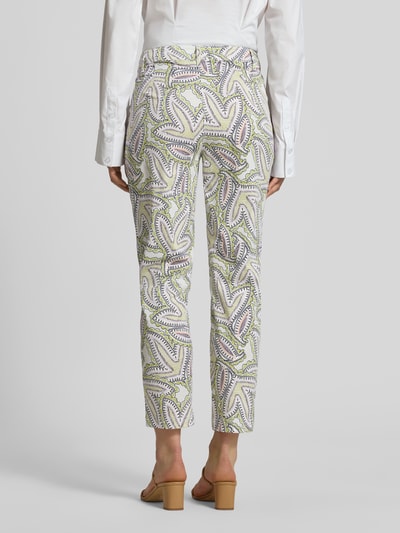 Vrouwenmodel draagt Hose im Allover-Look van Marc Cain in wit met groen en paars, katoen- en viscosemix, slim fit, all-over look, knoop- en ritssluiting, bandwijdte maat 36: 39 cm, binnenbeenlengte maat 36: 66 cm, geheel van achteren gezien.