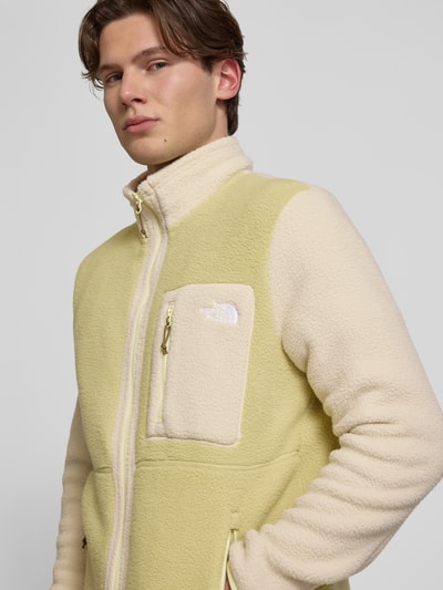 Männermodel trägt Fleecejacke mit Label-Stitching Modell 'Yumiori' von The North Face in Beige und Gelb, Reißverschluss, Nahaufnahme Oberkörper, Regular Fit, Stehkragen, Reißverschlusstaschen, Rückenlänge 67 cm, Ärmellänge 70 cm, Größe M, Struktur aus weichem Fleece.