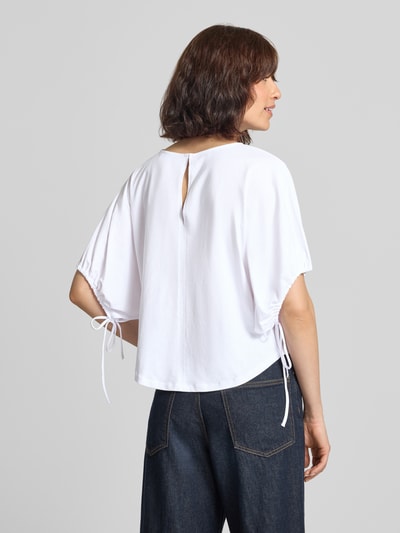 Frauenmodel trägt T-Shirt mit Motiv-Print und Kordelzug am Ärmel von Rich & Royal, reine Baumwolle, weiß, lockerer Schnitt, Rückenansicht, Ganzkörperansicht Rückansicht