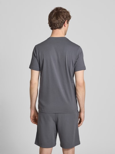 Männermodel trägt T-Shirt mit Label-Stitchings und Rundhalsausschnitt von CHAMPION, reine Baumwolle, regular Fit, Rückenansicht, Ganzkörperansicht Rückansicht.