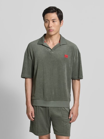 Männermodel trägt Regular Fit Poloshirt aus Baumwoll-Mix Modell 'TERRANCE' von HUGO in Optik: Unifarben, Relaxed-Fit, Label-Patch, Polokragen, Ärmelform: Kurzarm, Materialverarbeitung: Sweat, Material: Baumwoll-Mix; Ganzkörperansicht von vorne.