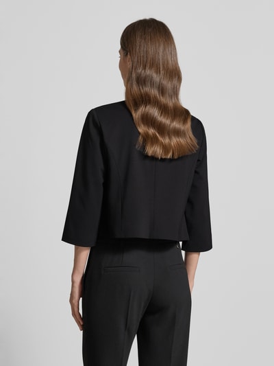 Männermodel trägt Blazer aus Viskose-Mix mit offener Front von Betty Barclay, czarny kolor, prosty krój, okrągły dekolt, rękaw 3/4, długość tyłu w rozmiarze 36: 43 cm, szerokość w rozmiarze 36: 45 cm, długość rękawa w rozmiarze 36: 39 cm, widok całej sylwetki z tyłu