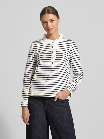 Frauenmodel trägt Longsleeve mit Knopfleiste und Rüschen von Christian Berg Woman, weiße Baumwolle, Regular-Fit, Stehkragen, Ganzkörperansicht von vorne.