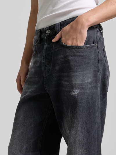 Männermodel trägt Wide Fit Jeans im 5-Pocket-Design von Diesel in dunklem Grau mit Logo-Patch aus reiner Baumwolle, Nahaufnahme Oberkörper.