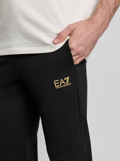 Männermodel trägt Sweatpants mit Logo und elastischem Bund von EA7 Emporio Armani, schwarzer Baumwoll-Elasthan-Mix, Nahaufnahme Oberschenkel.