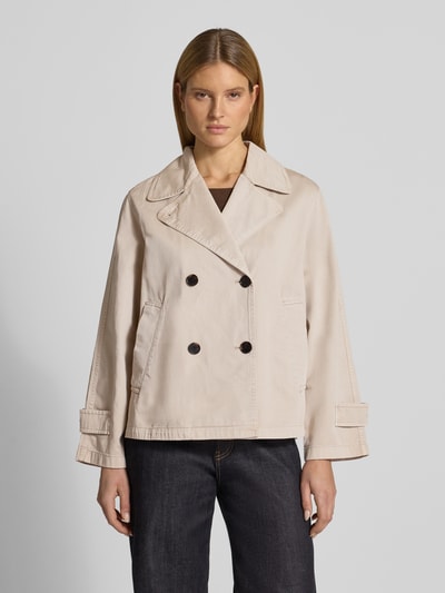 Kobiece modelka nosi Regular Fit Trenchcoat aus reiner Baumwolle von Marc O’Polo w jednolitym kolorze, długi rękaw z patkami, dwurzędowe zapięcie na guziki, boczne kieszenie wpuszczane, materiał bawełna, krój regular fit, widok całej sylwetki z przodu.