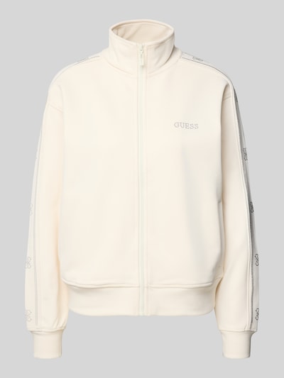 Produktfoto, cremefarbene Regular Fit Sweatjacke mit Viskose-Anteil Modell 'Octavia' von Guess Activewear, Stehkragen, Ziersteinbesatz, Logo-Detail, Reißverschluss und elastischen Abschlüssen, glatte Struktur.