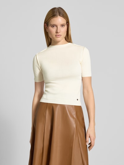 Frauenmodel trägt Slim Fit Strickshirt mit Woll-Anteil Modell 'CAROLINE' von Guido Maria Kretschmer WOMAN, Material-Mix, Stehkragen, 1/2-Arm, helle Farbe kombiniert mit braunem Rock, Rückenlänge 54 cm, Ärmellänge 23 cm, Ganzkörperansicht von vorne.