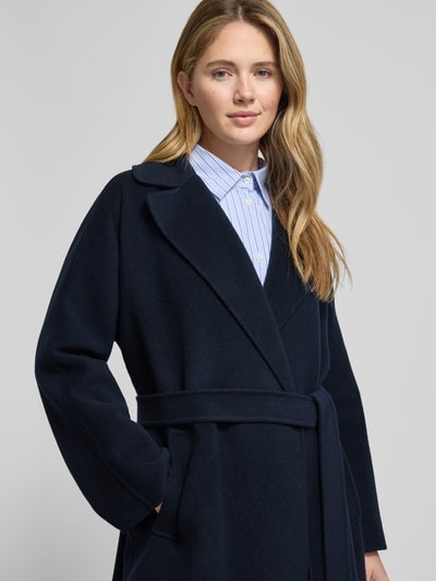 Frauenmodel trägt Regular Fit Wollmantel aus Schurwoll-Mix Modell 'CIVADA' von Weekend Max Mara in Dunkelblau, Nahaufnahme Oberkörper. Unifarbene Optik, Reverskragen, Bindegürtel, seitliche Eingrifftaschen, Label Stitching, langarm, weiche Textur.