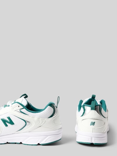 Produktfoto, Sneaker mit Kontrastbesatz von New Balance, weiße Oberfläche, grüne Details, strukturierte Sohle, seitliche und rückseitige Ansicht, abgerundete Form, Schnürverschluss, Label-Detail, Absatzhöhe 3 cm, Schafthöhe 8 cm, Schaftweite 9 cm