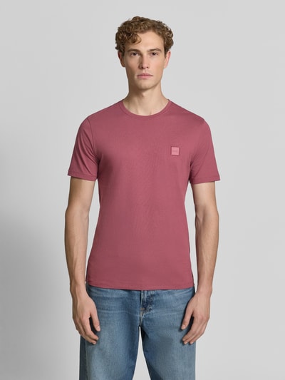 Męski model nosi Regular Fit T-Shirt aus reiner Baumwolle Modell 'TALES' von BOSS Orange, jednolity różowy kolor, tekstura gładka, Ganzkörperansicht von vorne.