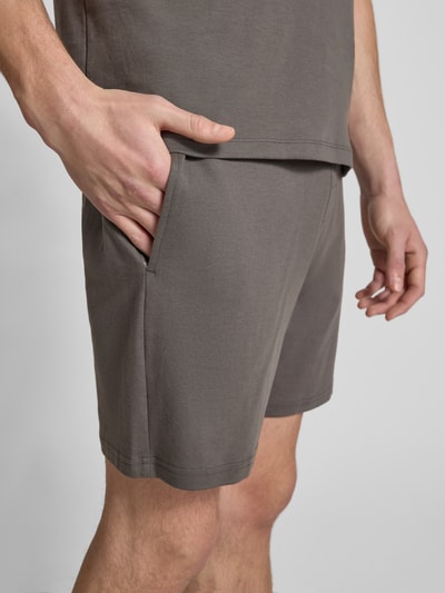 Męski model nosi Shorts mit elastischem Bund od Christian Berg Men, bawełna, luźny krój, tunel, szary, długość nogawki 18 cm, zbliżenie na biodra.