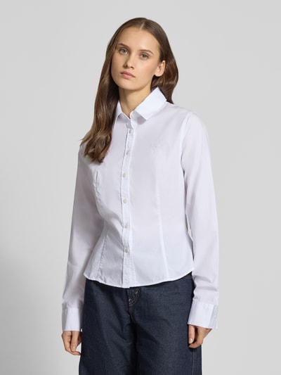 Frauenmodel trägt Slim Fit Bluse mit Knopfleiste von Guess Jeans, weiße Baumwolle, Hemdblusenkragen, lange Ärmel, Nahaufnahme Oberkörper.
