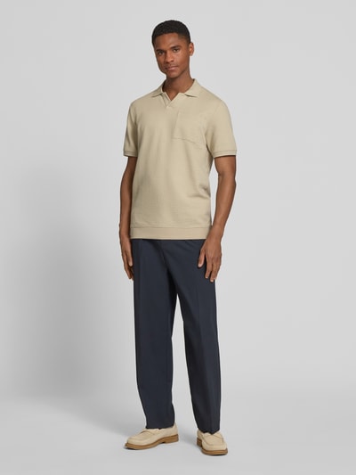 Männermodel trägt Regular Fit Poloshirt aus Baumwoll-Mix von s.Oliver RED LABEL in Beige, kurzarm, Polokragen, strukturierte Seersucker-Optik, unifarben, Ganzkörperansicht von vorne