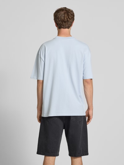 Männermodel trägt Oversized T-Shirt mit Label-Stitching von Pegador, Baumwoll-Mix, hellblau, Rundhalsausschnitt, Rückenlänge 70 cm, Ganzkörperansicht Rückansicht.