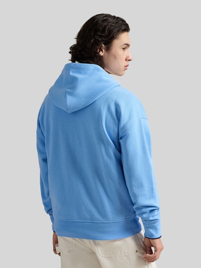 Männermodel trägt Relaxed Fit Sweatjacke aus Baumwoll-Mix von Polo Ralph Lauren in Hellblau mit Kapuze, gerippten Abschlüssen, Ganzkörperansicht Rückansicht.