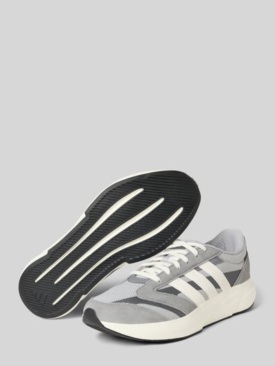 Produktfoto, grau-weißer Sneaker mit Schnürung Modell 'LIGHTSHIFT 2.0' von adidas Sportswear, Gummisohle, abgerundete Spitze, Absatzhöhe 5 cm, Schafthöhe 7 cm, Schaftweite 7 cm, klare Linien und strukturierte Texturen.