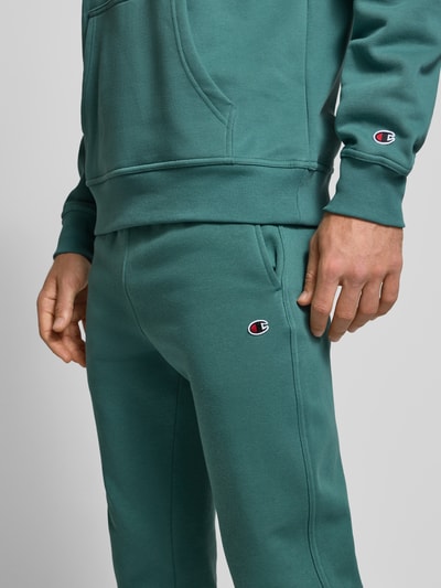 Männermodel trägt Sweatpants mit elastischem Bund und Label-Stitching von CHAMPION aus Baumwoll-Mix, Regular-Fit, Nahaufnahme Oberkörper.