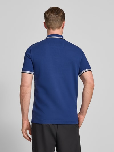 Männermodel trägt Regular Fit Poloshirt aus reiner Baumwolle Modell 'PADDY' von BOSS Green in Blau, Piqué-Struktur, Ganzkörperansicht Rückansicht.