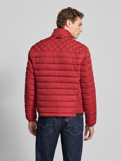 Männermodel trägt Slim Fit Steppjacke mit gefüttertem Kragen von Christian Berg Men, czerwona, poziome przeszycia, krój slim fit, kieszenie zapinane na zamek błyskawiczny, elastyczne zakończenia rękawów, długość tyłu w rozmiarze M: 68 cm, szerokość ramion w rozmiarze M: 47 cm, szerokość w rozmiarze M: 52 cm, długość rękawów w rozmiarze M: 68 cm, widok z tyłu na całe ciało
