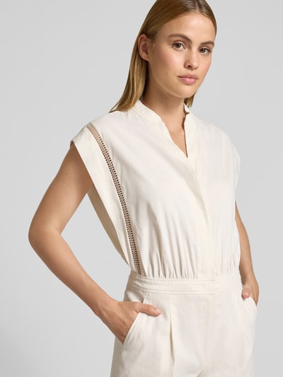 Frauenmodel trägt Jumpsuit aus Leinen-Mix mit Loch-Stickerei von Marc Cain in Creme, tailliert, V-Ausschnitt, Loch-Stickerei, Nahaufnahme Oberkörper.