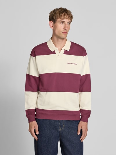 Mannenmodel draagt Relaxed Fit Troyer aus reiner Baumwolle van Marc O'Polo DENIM in bordeauxrood en crème met brede strepen, katoen, ganzlichaamsvooraanzicht.