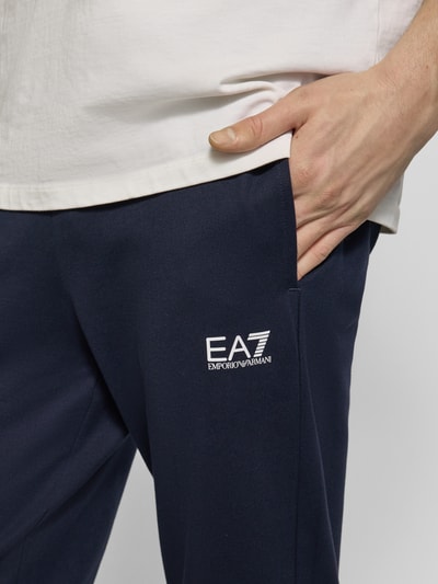 Männermodel trägt Sweatpants mit Logo und elastischem Bund von EA7 Emporio Armani in Dunkelblau, Regular Fit, Nahaufnahme Oberkörper.