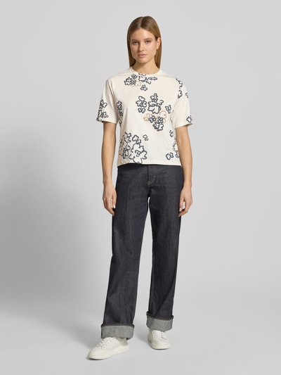 Modelka kobieca ma na sobie T-Shirt im Allover-Look mit Rundhalsausschnitt od JAKE*S STUDIO WOMAN, bawełna, krój relaxed fit, jasna tkanina z ciemnoniebieskim wzorem, długość tyłu w rozmiarze S: 56 cm, całkowity widok z przodu.