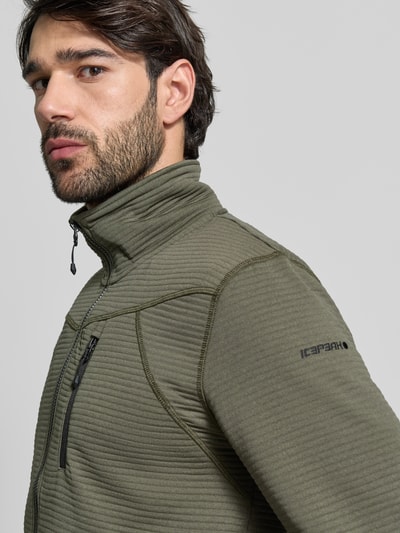 Männermodel trägt Regular Fit Jacke mit Stehkragen Modell 'Berthold' von Icepeak in Olivgrün mit Reißverschluss und Napoleontasche, Nahaufnahme Oberkörper. Rückenlänge 74 cm, Schulterbreite 46 cm, Brustweite 52 cm, Ärmellänge 71 cm. Strukturierte Textur, elastische Abschlüsse.