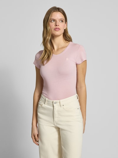 Kobiece modelka ma na sobie T-shirt mit Label-Stitching od G-Star Raw z czystej bawełny, krój slim fit, prążkowany okrągły dekolt, długość tyłu 57 cm w rozmiarze S, jasnoróżowy, gładka tekstura, widok całej sylwetki z przodu.