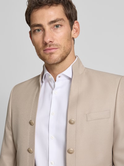 Męski model nosi marynarkę 'Sakko mit Knopfleisten und Label-Patch' od Wilvorst, mieszanka materiałów z dodatkiem wełny, taliowany krój, otwarty przód, stójka, listwy guzikowe, brustasza, kieszenie z wypustkami, naszywka z logo, jasny beż, gładka tekstura, detailaufnahme górnej części ciała.