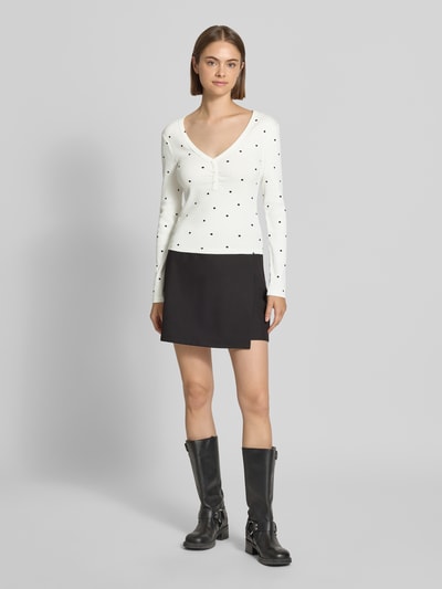 Frauenmodel trägt Regular Fit Langarmshirt aus Baumwoll-Mix Modell 'FENJA' von ONLY, weiß mit schwarzen Punkten, glatte Struktur, Ganzkörperansicht von vorne, Damen Langarmshirt von ONLY