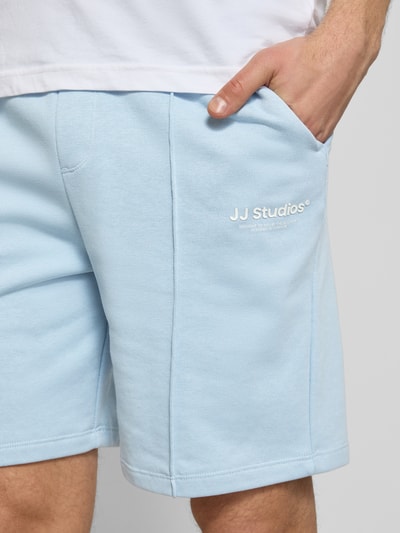Mannenmodel draagt Sweatshorts met Logo Model 'KANE' van Jack & Jones, katoenmix, relaxed fit, elastische band, logoprint, detailopname heup.