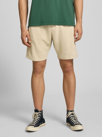 Męskamodel nosi Shorts mit Label-Patch Modell 'LIBCO' od Pegador, beżowy materiał z bawełnianą domieszką, prosty krój, faktura, szeroki elastyczny pas, widok całościowy z przodu, Szerokość w rozmiarze M: 38 cm, długość nogawki wewnętrznej: 23 cm