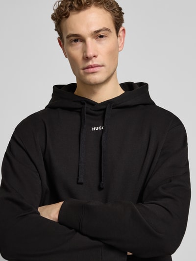 Männermodel trägt Regular Fit Hoodie aus reiner Baumwolle Modell 'DAPO' von HUGO, unifarben schwarz, Nahaufnahme Oberkörper.