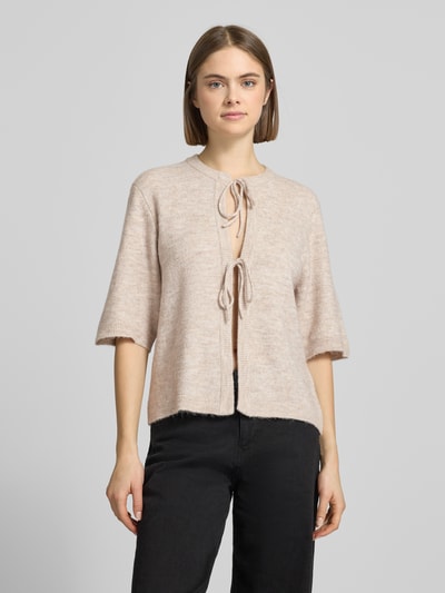 Frauenmodel trägt Regular Fit Cardigan mit Schnürungen Modell 'SIMONI' von Only, beige, unifarben, Strickoptik, Rundhals, Ganzkörperansicht von vorne.