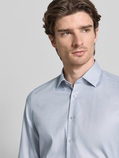 Männermodel trägt Slim Fit Business Hemd aus Baumwolle mit Kentkragen von OLYMP Level Five in Hellblau, glatte Textur, Nahaufnahme Oberkörper.