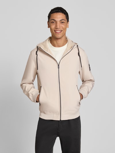 Männermodel trägt Regular Fit Jacke mit Logo-Detail von JACK & JONES in Beige, Kapuze, Reißverschlusstaschen, Ganzkörperansicht von vorne.