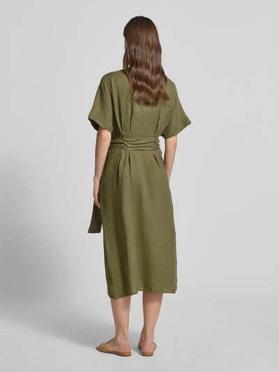 Frauenmodel trägt Midikleid aus reinen Leinen mit Tunika-Ausschnitt Modell 'Soli' von Christian Berg Woman Selection in Olivgrün, Kurzarm, taillierte Passform, abnehmbares Stoffband, knielang, Rückansicht Ganzkörperansicht.