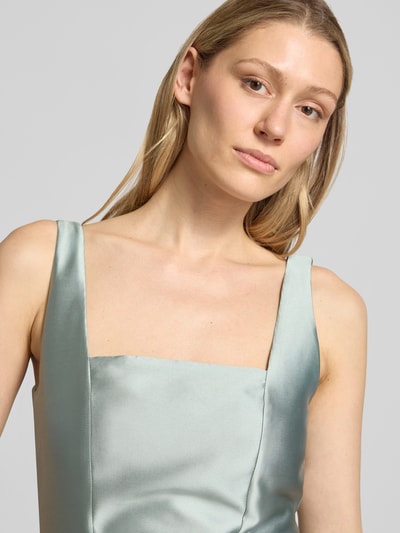 Frauenmodel trägt Cocktailkleid mit Karree-Ausschnitt von Swing, glänzender Stoff in Pastell, taillierte Passform, Nahaufnahme Oberkörper.