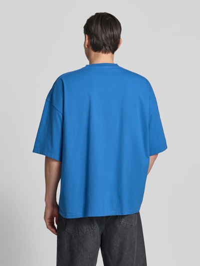 Männermodel trägt Herren T-Shirt mit Logo-Print Modell 'GIXY' von American Vintage in Blau aus Reine Baumwolle, Loose-Fit, Ganzkörperansicht Rückansicht.