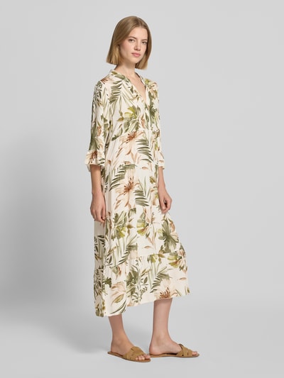 Frauenmodel trägt Midikleid aus Viskose mit Serafino-Kragen Modell 'Kl44arraa' von ZABAIONE mit tropischem Print, Ganzkörperansicht von vorne. Gerade Passform, Volantsaum, 1/2-Arm, Rückenlänge 113 cm, Brustweite 53 cm, Ärmellänge 43 cm.