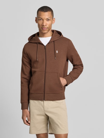 Męski model nosi Regular Fit Sweatjacke aus Baumwoll-Mix von Polo Ralph Lauren w jednolitym brązowym kolorze, z kapturem, suwak, długie rękawy, kieszenie naszywane, detal z logo, materiał sweat, bawełniany miks, całkowity widok z przodu.