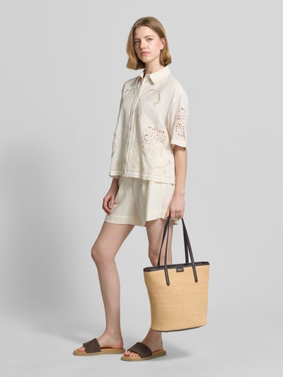 Frauenmodel trägt Shopper mit Label-Detail Modell 'JALA SHOPPER' von BOSS, beige Struktur, schwarze Henkel, Ganzkörperansicht von vorne.